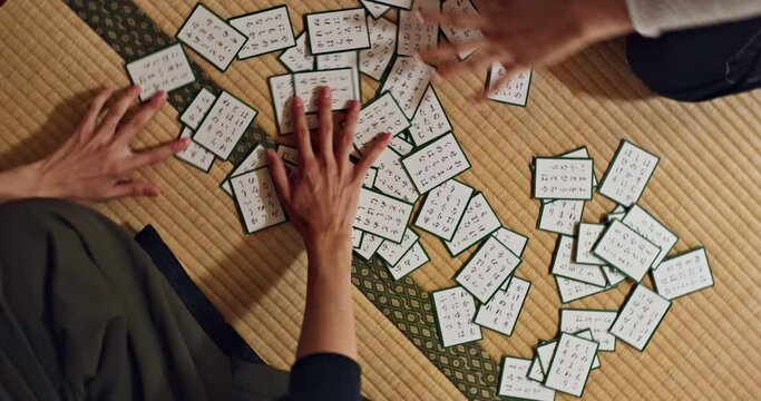 Hands, Cards And Game On Floor In Home For Challenge, Contest Or Problem Solving With Clue, Deal Or Deck. People, Closeup Or Above Karuta Competition With Paper, Reading Or Together To Relax On Mat