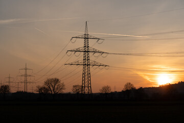 Silhouette of powerlines with the red glowing sun in the evening