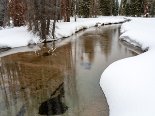 Beautiful little stream in winter with snow covered banks