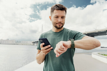 Man with smartphone checking time outdoors, combining technology with active urban lifestyle.