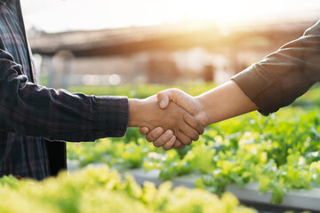 Two farmers hold hands and make an agreement on a contract for farming. Agribusiness concept. Lease...
