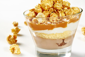 Glass of layered caramel popcorn dessert with sponge cake