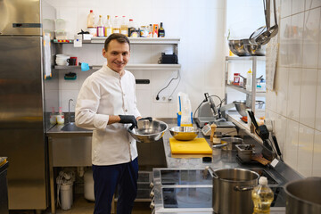 Smiling young chef preparing food in a restaurant kitchen