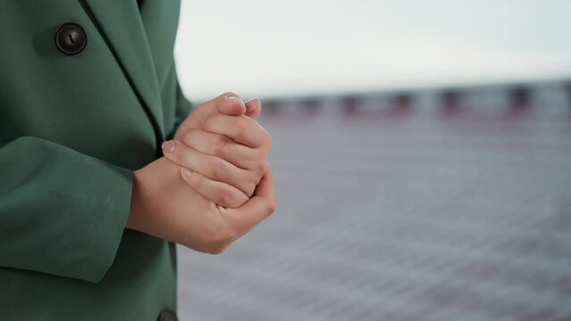 Nervous woman rubs hands on roof closeup