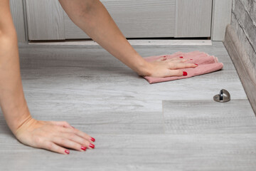 woman with manicure washes the floor with a rag