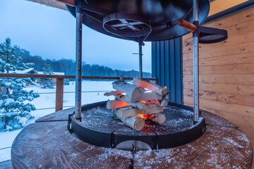 Barbecue grill with stacked firewood to kindle a fire. Wooden terrace on the background of a...