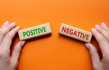 Positive or Negative symbol. Concept word Positive or Negative on wooden blocks. Businessman hand. Beautiful orange background. Business and Positive or Negative concept. Copy space