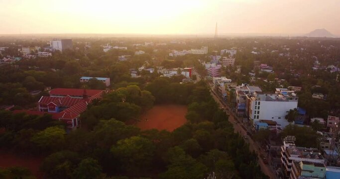 Aerial view above Nagercoil town, Kanyakumari District showing trees around the buildings at sunset