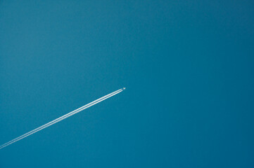 Looking up at a jet and contrail against a blue sky.