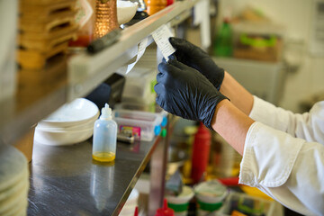 Kitchen worker in black protective gloves looks through a receipt
