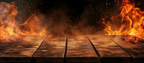 Rolgordijnen empty wooden table and burning fire on black background © zaen_studio