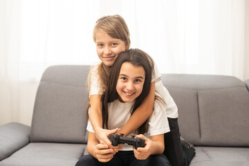 Two sisters kids playing video games at home together. Happy childeren, carefree childhood concept