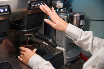 Woman barista prepares coffee in a coffee machine