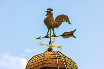 Beautiful view of weather vane in the form of a metal rooster and an arrow with directions of the...