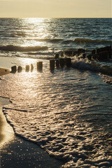Sunset over the sea. Reflection of sunlight in the sea waves. Breakwater in the sea. The sky in the sunset rays. Baltic Sea.