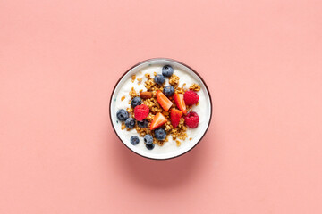 Healthy breakfast bowl with ingredients granola fruits Greek yogurt and berries on a pink background top view. Weight loss, healthy lifestyle and eating concept - obrazy, fototapety, plakaty