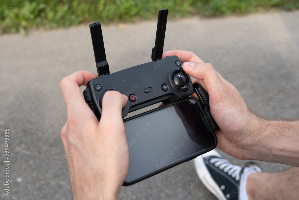 Wall mural man operating drone/man holding remote control drones/drone controller