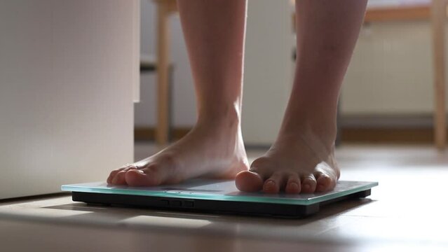 Woman On Scales Measure Weight.Human Barefoot Measuring Body Fat Overweight.Girl Legs Step On  Scale.Close Up Woman Checking Diet Female Feet Standing Weighing Scales On Room