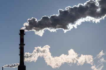 Industrial pollution of the environment. Plumes of smoke from a chimney in backlight.
