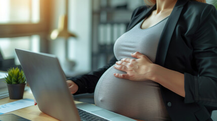 pregnant woman in a professional setting, working on a laptop.