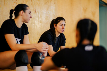 Teenage volleyball players sitting on court and taking a break.