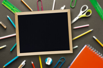 Back to School Concept. Blank school board on blurred background of stationery. Theme for beginning of school year. First day of preschool. Copyspace, place for text, message, design.