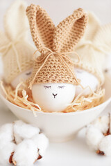 Easter eggs in crochet knitted hats with rabbit ears in nest. Easter celebration concept