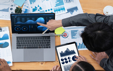 Multiracial analyst team use BI Fintech software to analyze financial data on meeting table....
