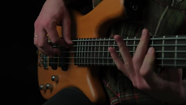 Close up video of man playing at 5 string bass.