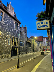 A view of a charming street in an old medieval town under a fish and chips sign