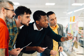 Diverse team of businessman writing their ideas on a sticky notes in the office