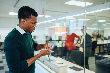 African american business man writing on a sticky notes on a glass wall