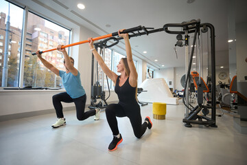 Fototapeta premium Middle-aged woman and man are doing warm-up with special stick