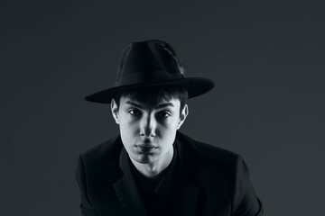 Naklejka premium portrait of a young man in a suit with a hat, shot in the studio in black and white