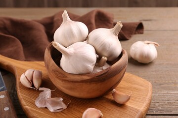 Fresh garlic and knife on wooden table, closeup