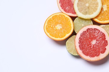 Different cut citrus fruits on white table, flat lay. Space for text