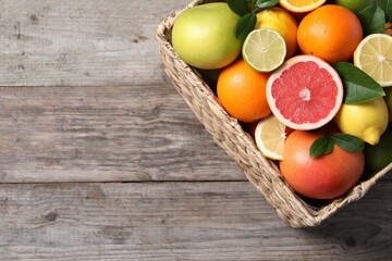 Different cut and whole citrus fruits on wooden table, top view. Space for text