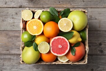 Different cut and whole citrus fruits on wooden table, top view