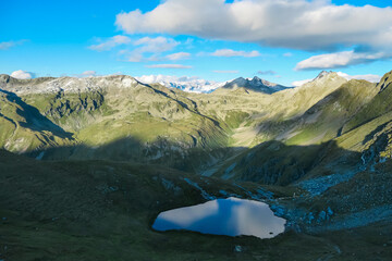 Idyllic alpine lake with sunrise view of majestic snow capped mountain peak Mallnitzriegel, High...