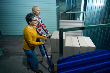 Man and a woman pushing a cart with cardboard boxes