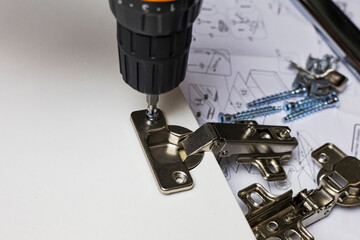 Installing a furniture hinge on the door. Assembling furniture and fixing fittings close-up....