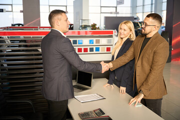 Male buyer shaking hands with car salesman