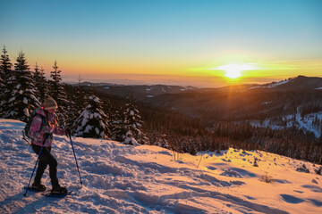 Sport woman in snow shoes enjoying beautiful sunrise over alpine landscape of Kor Alps, Carinthia...