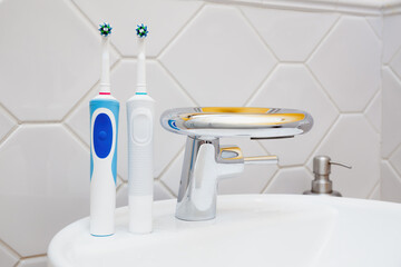 Modern Electric Toothbrushes by Bathroom Sink - obrazy, fototapety, plakaty