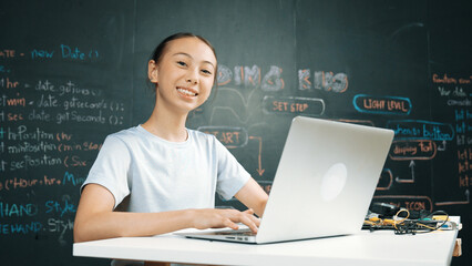 Smart girl programing system by using laptop at blackboard. Highschool student writing engineering...