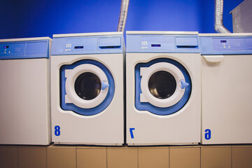 Professional washing machines with baskets full of clothes at the self-service laundry.