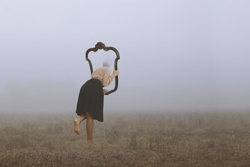 .surreal journey of a woman who escapes from the real world through a frame immersed in fog, abstract concept - 739536543
