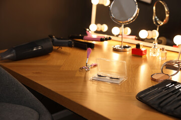 Eyelashes, different makeup products and tools on wooden table indoors