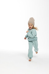  Portrait of beautiful cute little toddler girl. Child with funny face in mint sweatshirt and hat. Pretty smile kid in studio on white background.
