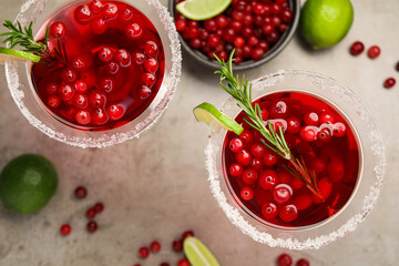 Tasty cranberry cocktail with rosemary and lime in glasses on grey table, flat lay